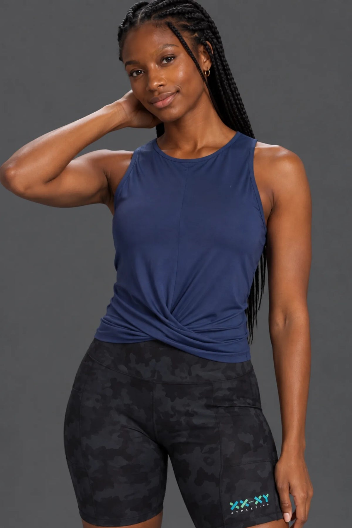 Black woman with braids wearing a navy twist-front tank and black camo bike shorts. || Indigo