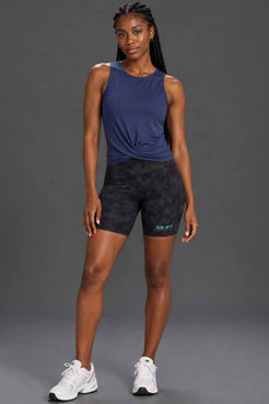 Black woman wearing a navy twist-front performance tank with black camo bike shorts. || Indigo