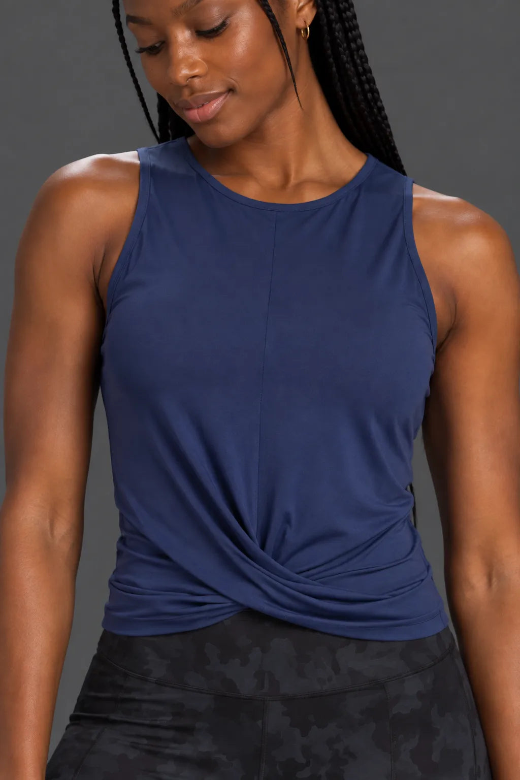 Close-up of navy twist-front performance tank showing the crossover hem detail.