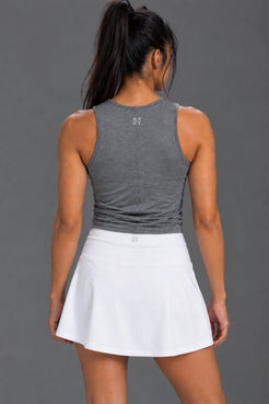 Back view of female model wearing a gray textured tank top with a white athletic skirt. || Dark Heather Gray