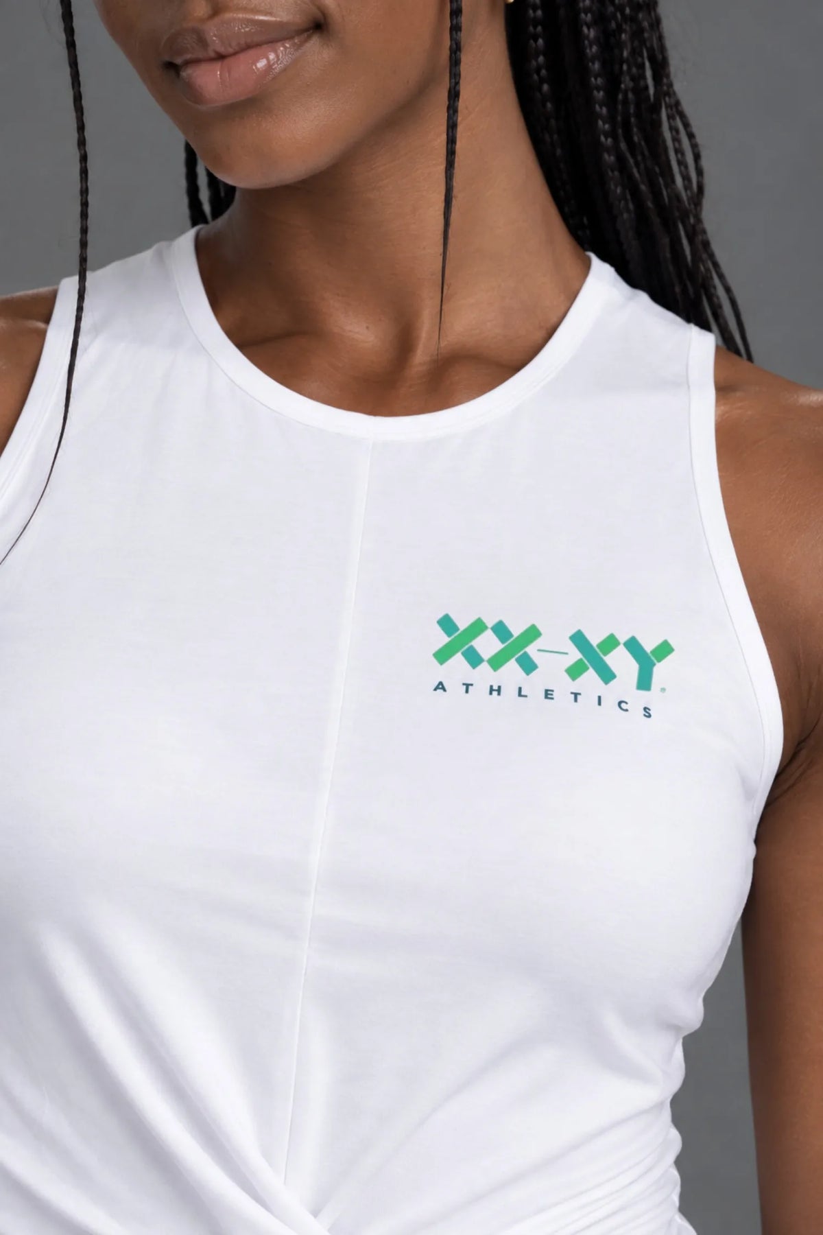 Close-up of white XX-XY Athletics twist-front tank top showing the chest logo and fabric details. || White