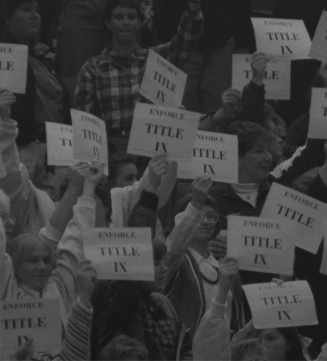People holding signs enforcing Title IX in a crowd