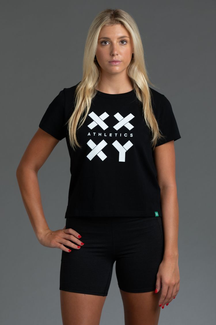 Woman wearing a black t-shirt with a logo on a gray background || Black - White Logo