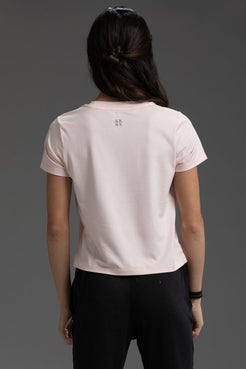 Person wearing a light pink t-shirt with text on the back against a gray background || Light Pink Heather