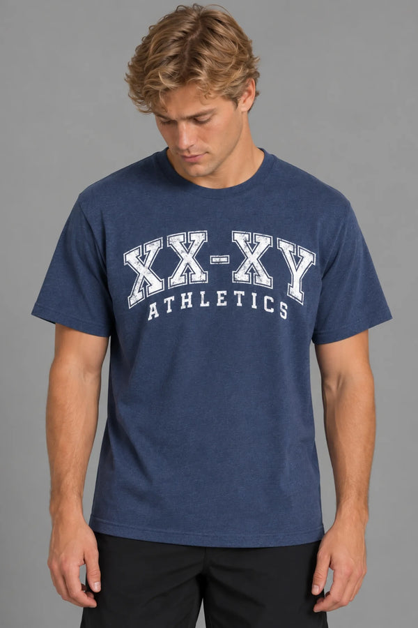 Male model looking down while wearing the XX-XY Athletics Varsity Logo Tee, featuring a distressed white collegiate-style graphic across the chest || Navy