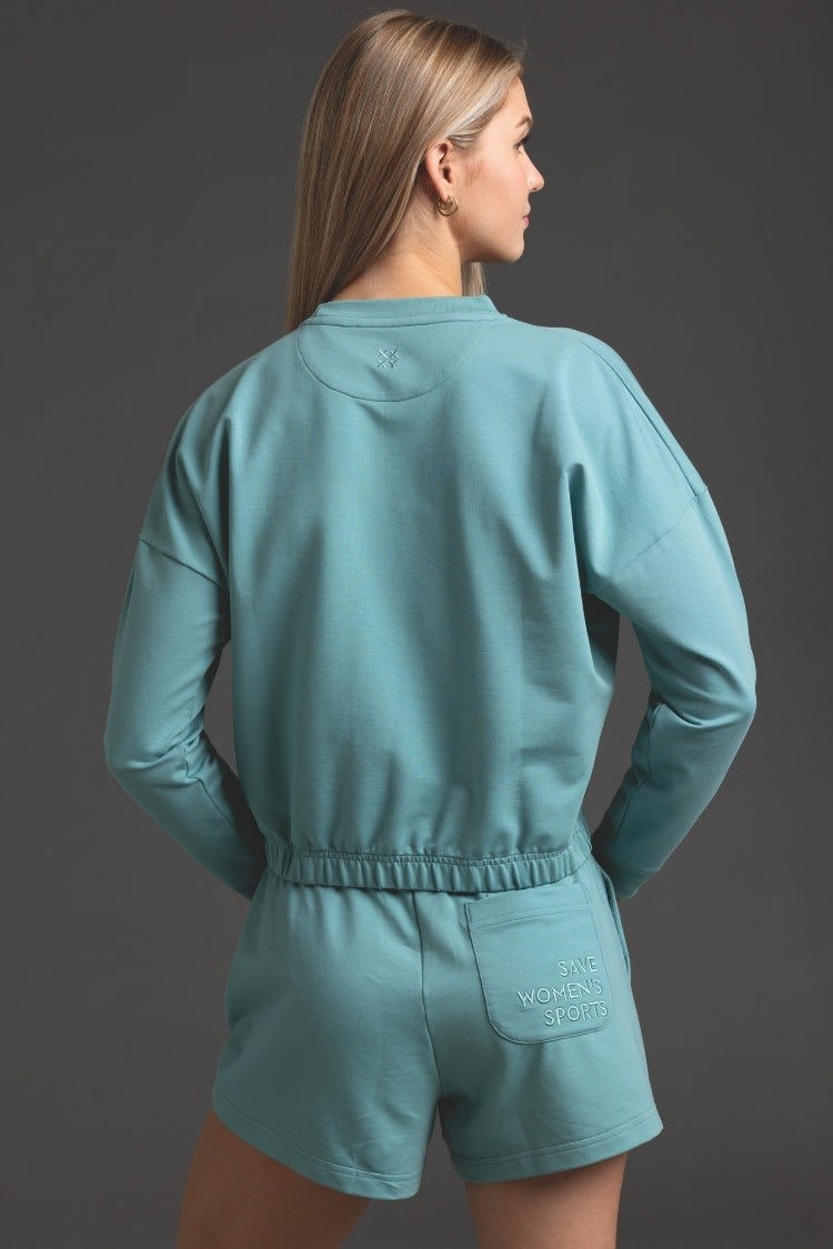Person wearing a teal outfit with 'Ninety Percent' branding on a gray background