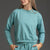 Woman wearing a teal sweatshirt and shorts set against a gray background || Underseas