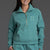 Woman wearing a teal tracksuit with a logo on a gray background || Underseas