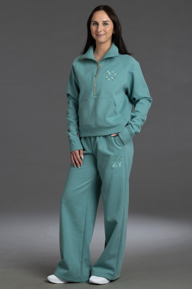 Woman wearing a teal tracksuit against a gray background || Underseas