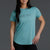 Woman wearing a teal t-shirt with a logo on a gray background || Underseas