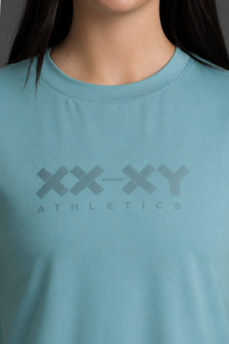 Teal athletic shirt with 'XX-XY Athletics' logo on a plain background