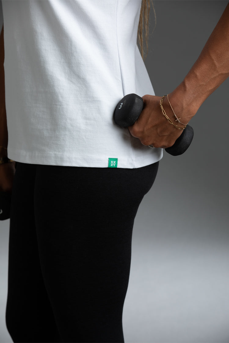 Person holding a dumbbell wearing a white shirt with a green logo and black pants || Taupe
