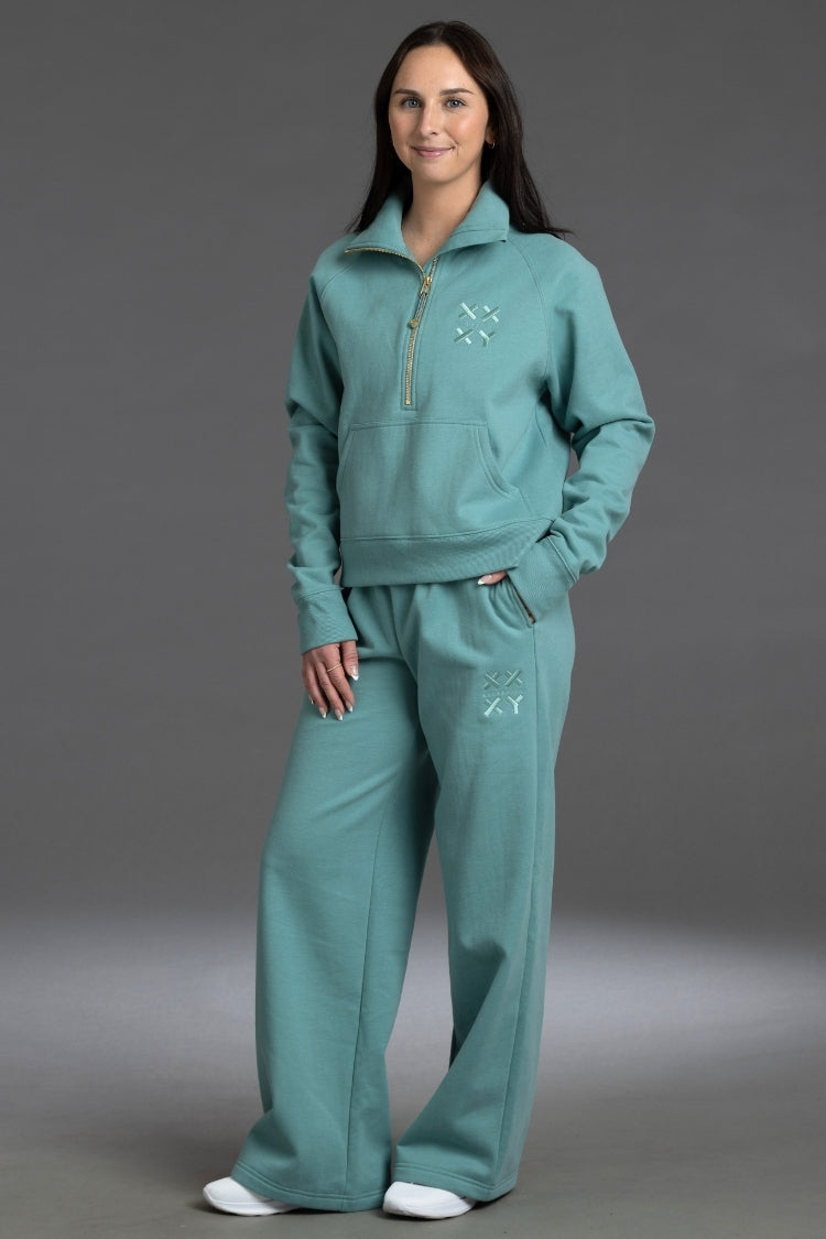 Woman wearing a teal tracksuit against a gray background || Underseas