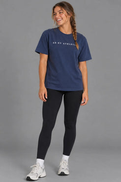 Close-up of female model wearing the XX-XY Athletics Wordmark Logo Boyfriend Tee, highlighting the white chest logo and navy cotton fabric || Navy