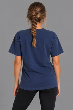 Female model showcasing the plain back of the XX-XY Athletics Wordmark Logo Boyfriend Tee, paired with black leggings and a loose braid || Navy