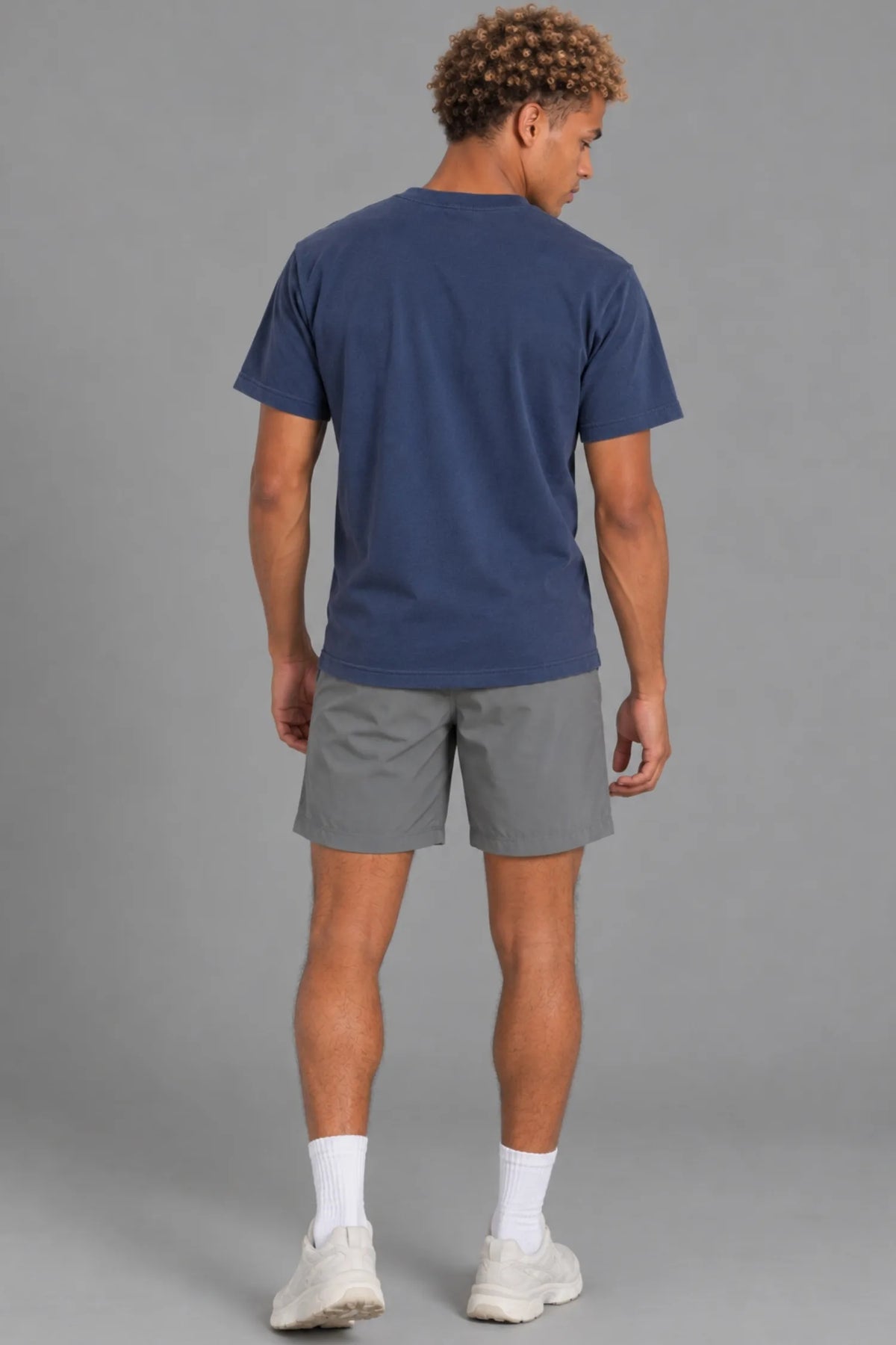 Male model showcasing the plain back of the XX-XY Athletics Wordmark Logo Tee, paired with gray shorts || Navy