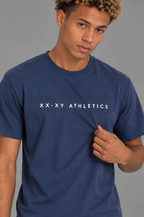 Close-up of male model wearing the XX-XY Athletics Wordmark Logo Tee, highlighting the white chest logo and cotton fabric || Navy