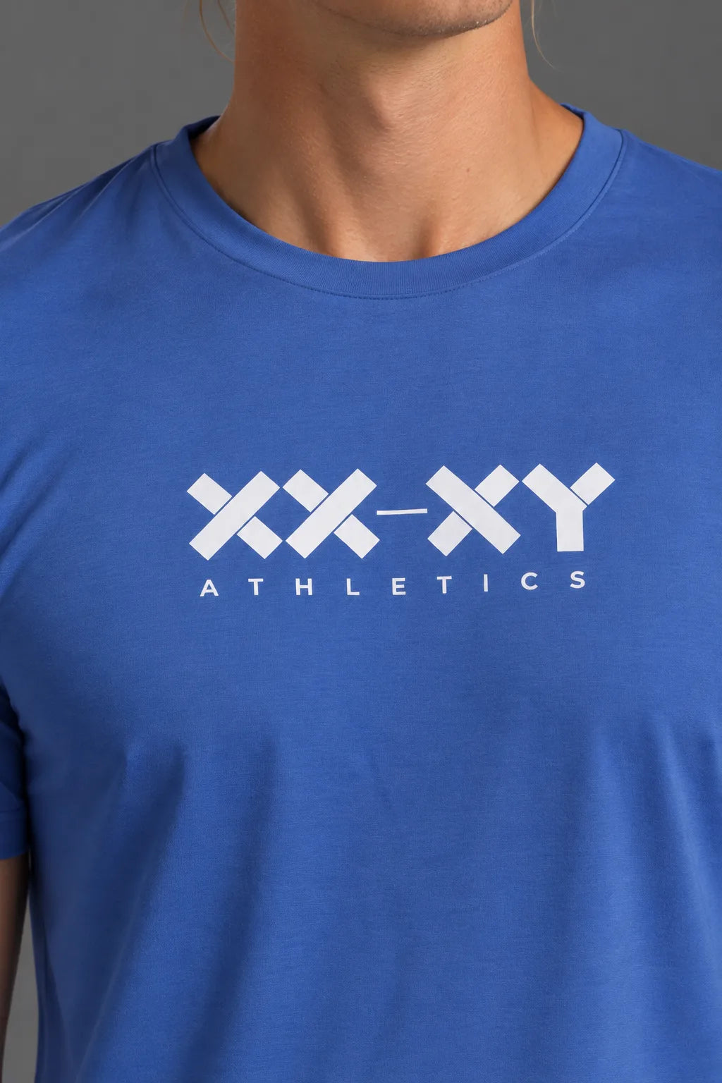 Close-up of the white XX-XY Athletics logo on the blue men’s tee.
