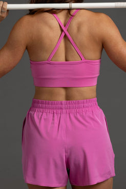 Person wearing a pink sports bra and shorts on a gray background || Bright Fuchsia