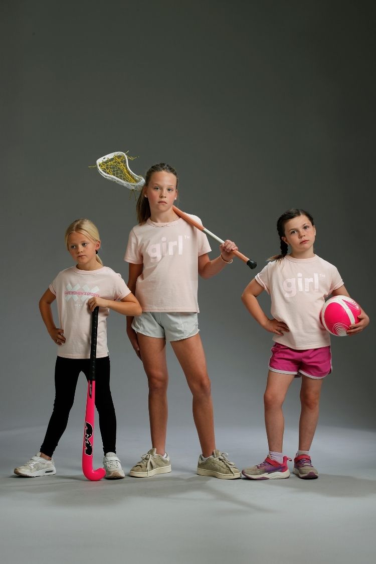 Three young girls holding sports equipment against a gray background || light pink