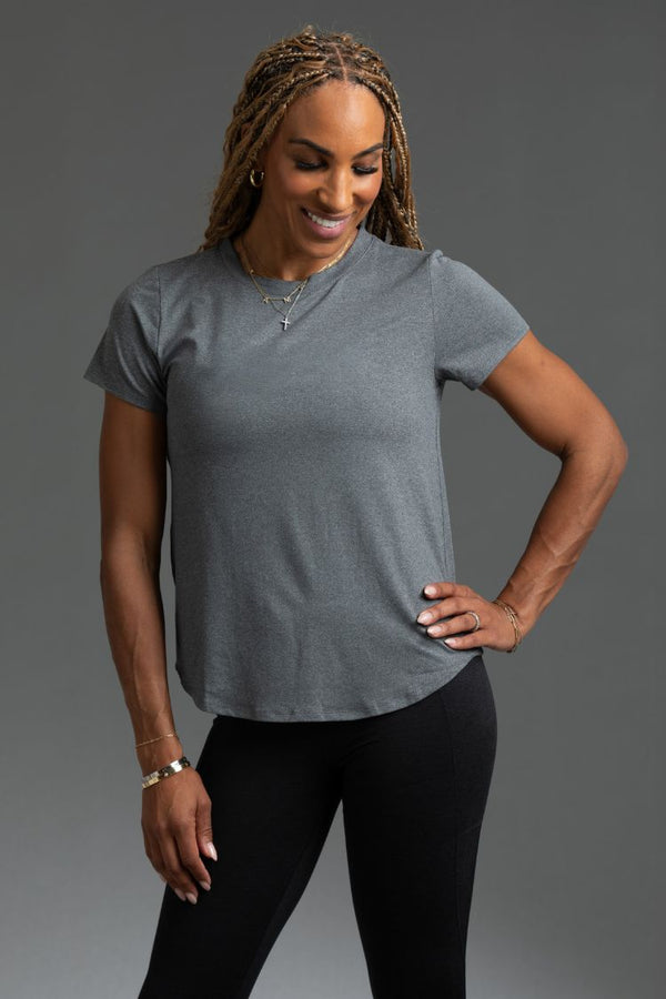 Woman wearing a gray t-shirt and black leggings against a gray background || Dark Heather Gray