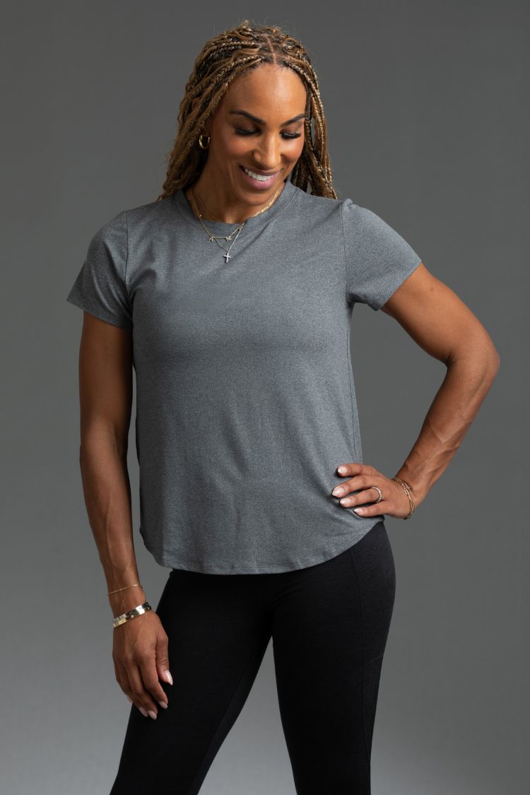 Woman wearing a gray t-shirt and black leggings against a gray background || Dark Heather Gray