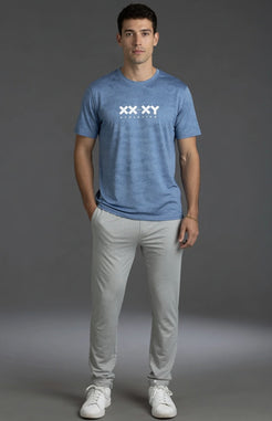 Man wearing a blue t-shirt with a logo and light gray pants on a gray background || Light Heather Gray - 1