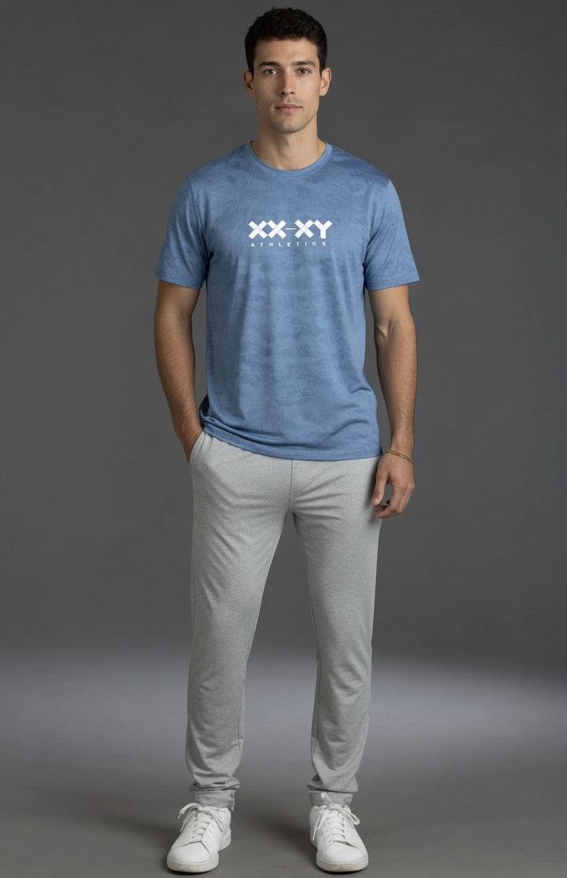 Man wearing a blue t-shirt with a logo and light gray pants on a gray background || Light Heather Gray - 1