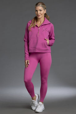 Woman wearing a pink tracksuit with a logo on a gray background || Bright Fuchsia