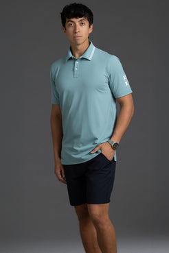 Man wearing a light blue polo shirt and dark shorts against a gray background || Underseas