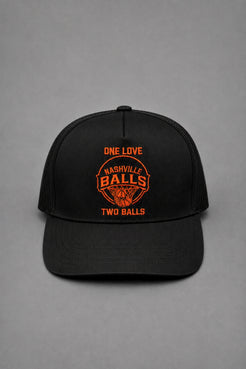 A black trucker-style baseball cap with orange embroidered text and a basketball graphic on the front, photographed against a neutral gray background. || Black