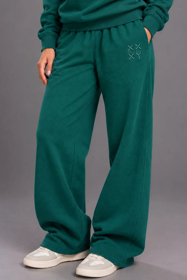 Close-up of pine green XX-XY Athletics wide-leg sweatpants featuring a tonal embroidered thigh logo. || Pine