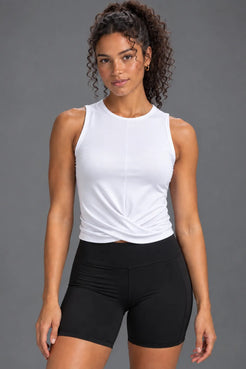 Woman wearing a white twist-front performance tank with black bike shorts. || White