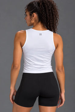 Back view of woman wearing a white performance tank with XX-XY logo and black bike shorts. || White