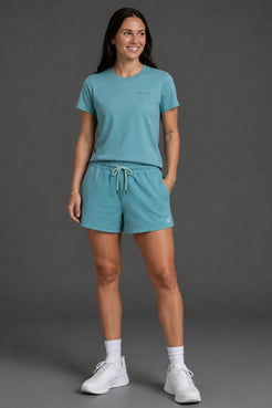 Woman wearing a teal athletic outfit with white sneakers on a gray background || Underseas