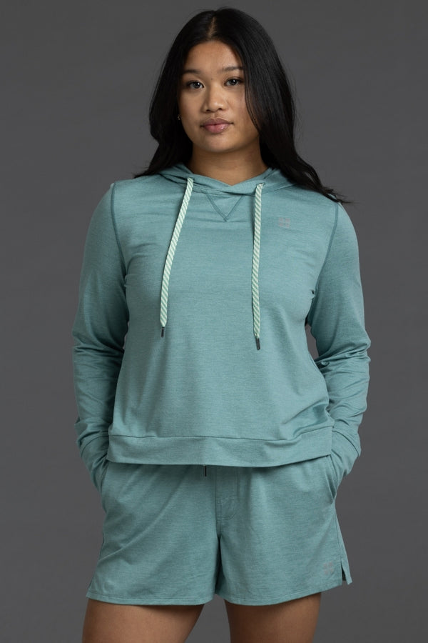 Woman wearing a teal hoodie and shorts set on a gray background || Underseas