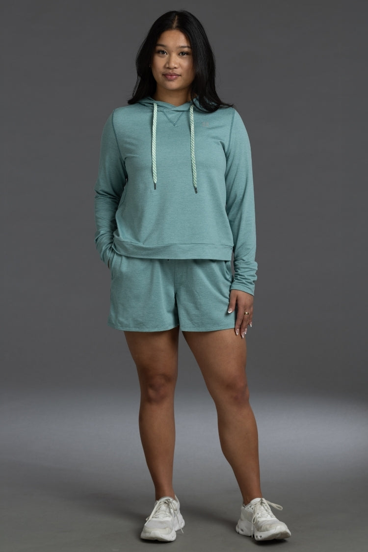 Woman wearing a teal hoodie and shorts set on a gray background || Underseas